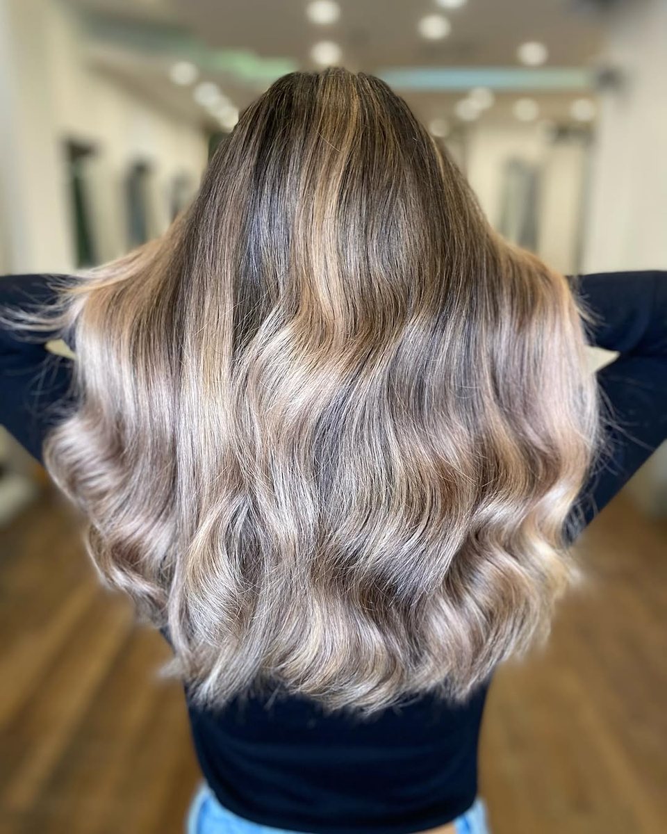 Balayage blond froid fondu sur cheveux longs ondulés, vue de dos